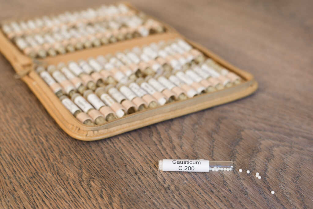 Globuli causticum und im Hintergrund eine Taschenapotheke mit Globuli